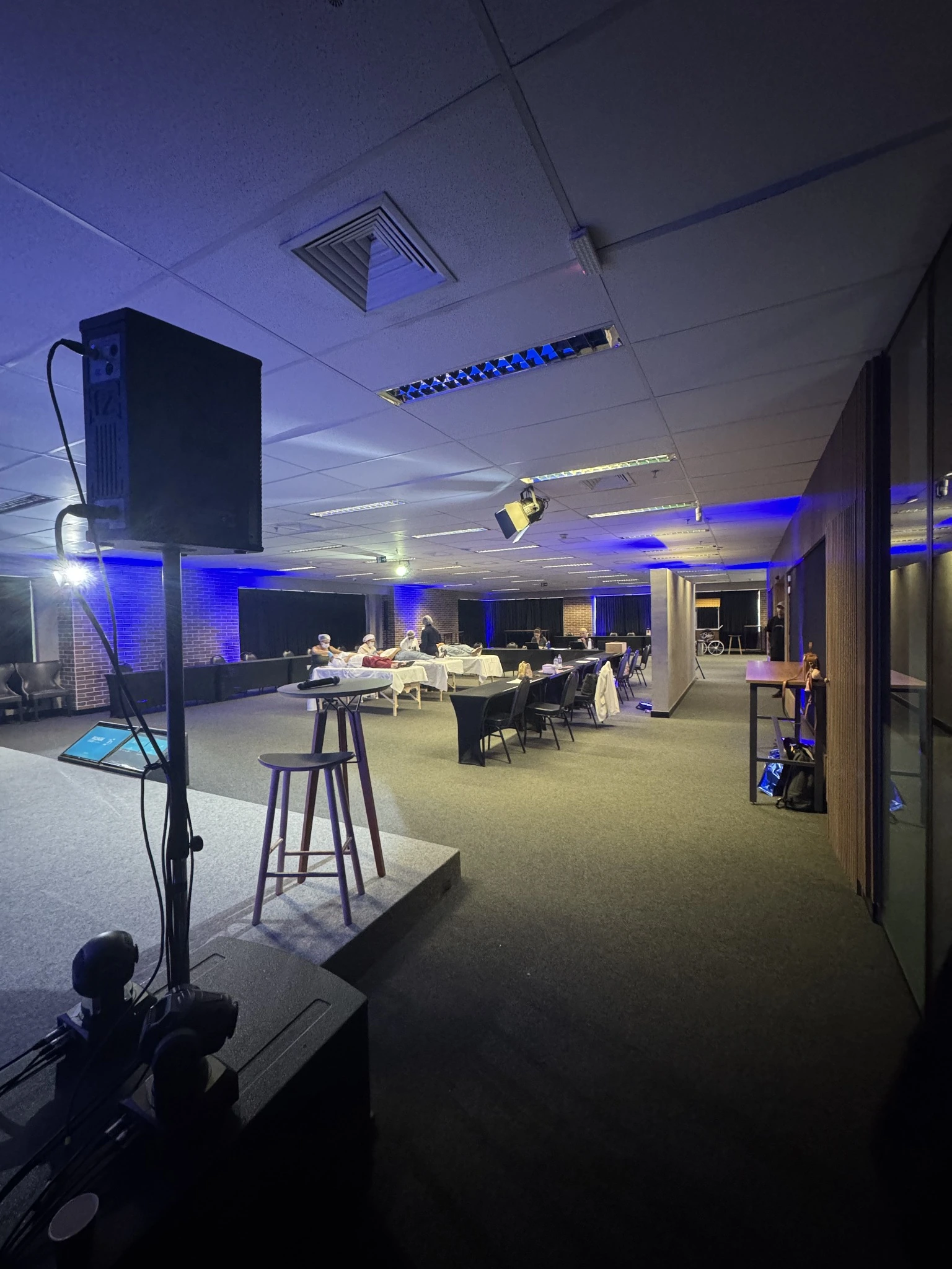 Espaço preparado para evento com estrutura técnica e iluminação azul