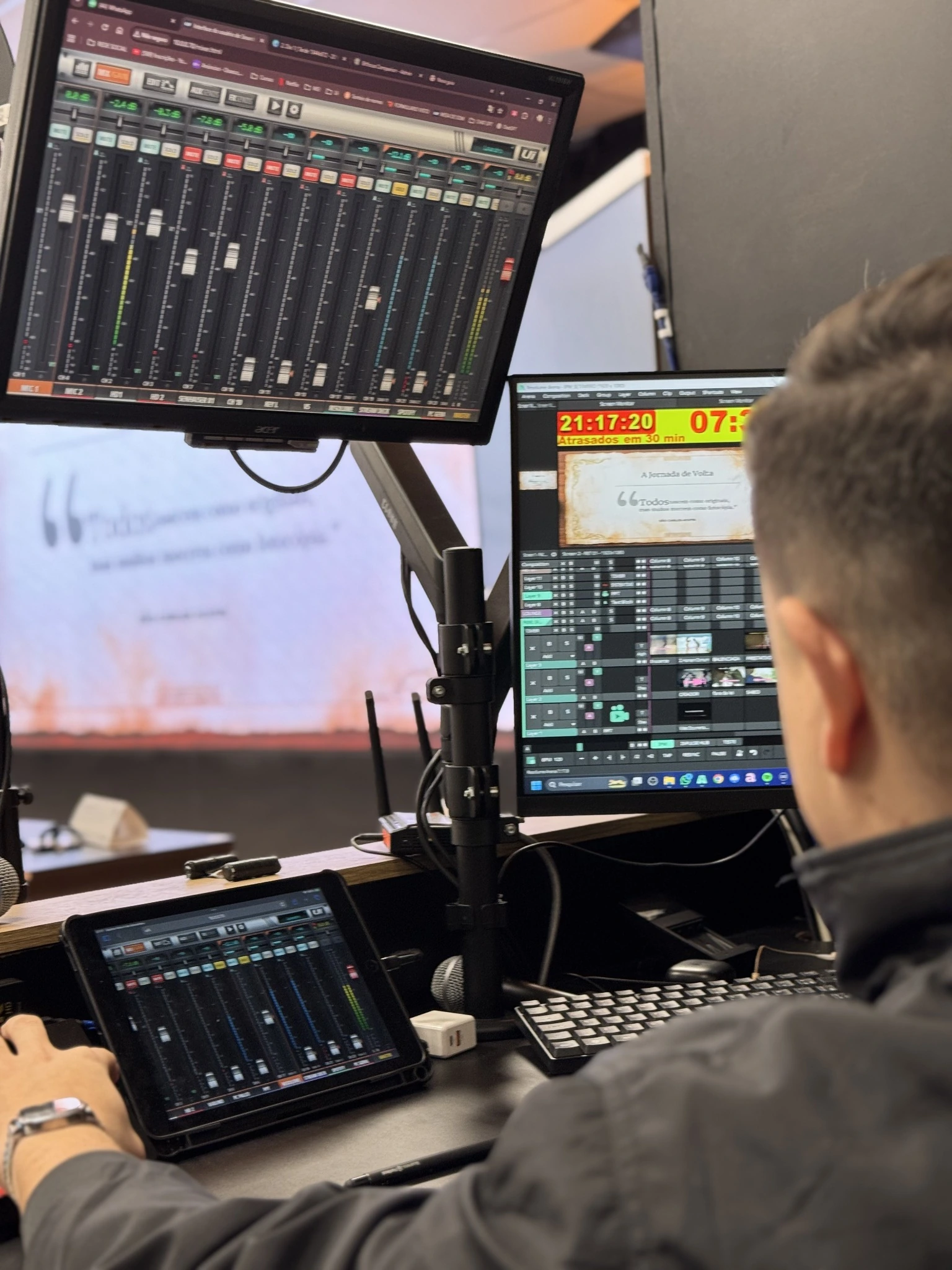 Técnico operando áudio e vídeo com telas digitais durante evento